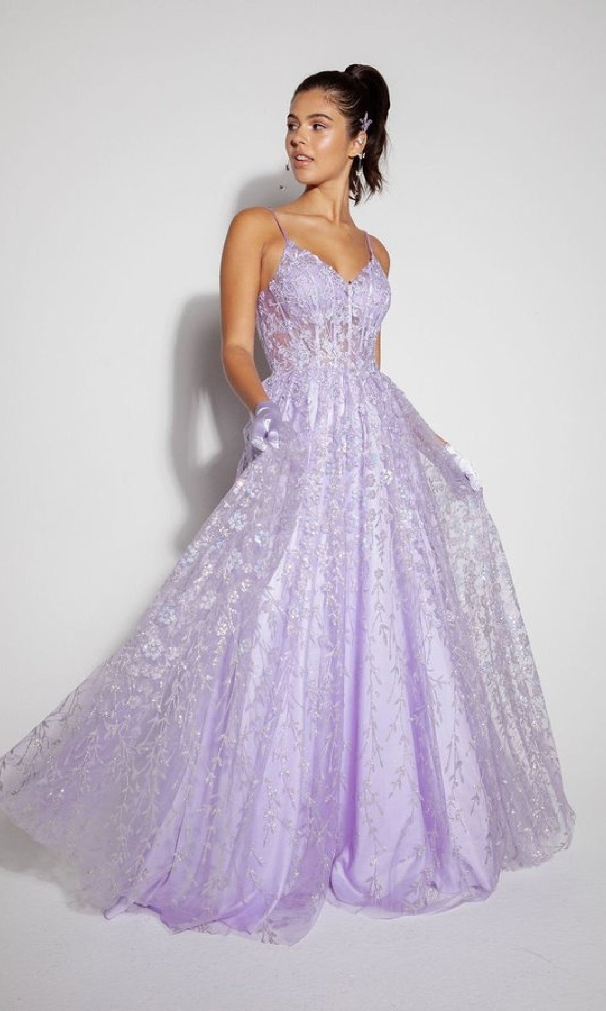 A woman stands against a plain background wearing the Long Glitter A-Line Prom Dress: Eureka 9908, featuring a lavender hue, sheer embroidered overlay, thin straps, and gloves.